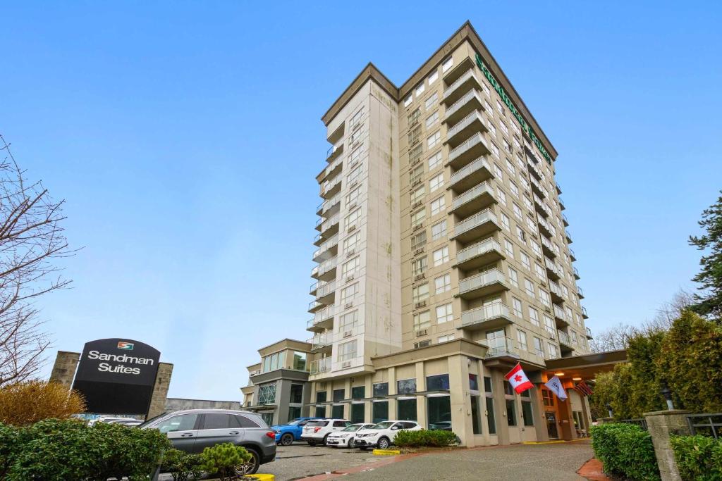 ein großes Gebäude mit Autos auf einem Parkplatz in der Unterkunft Sandman Suites Surrey - Guildford in Surrey