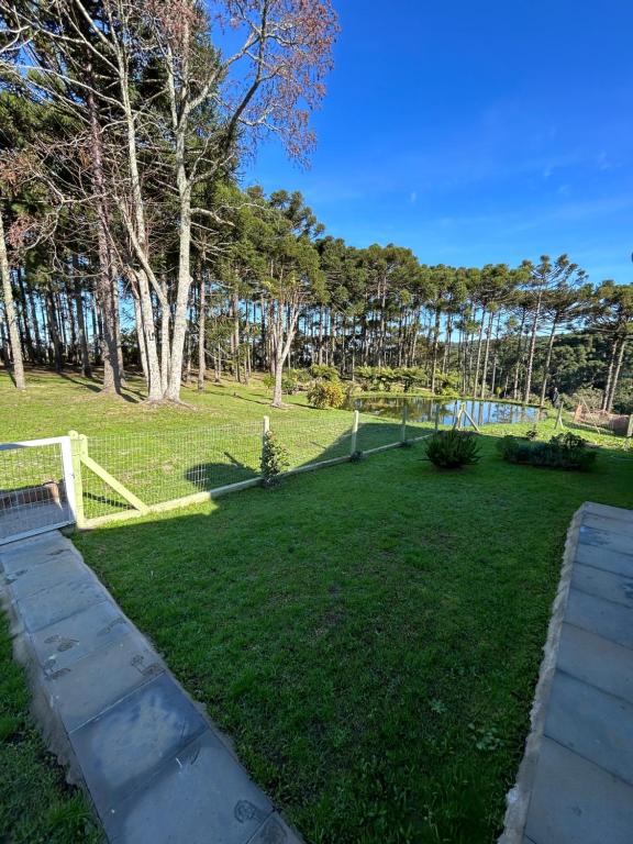 a grassy yard with a fence and trees at Recanto das Araucárias - Carazal, Gramado. in Gramado