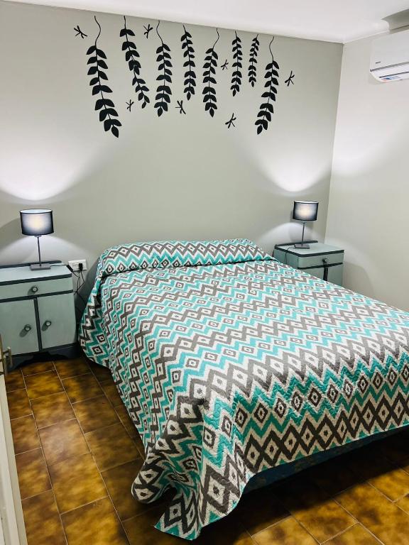 1 dormitorio con 1 cama con edredón verde y 2 lámparas en Departamento céntrico en Lujan de Cuyo en Luján de Cuyo