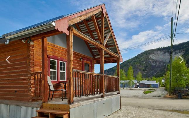 a wooden cabin with a chair on the porch at Klondike Kate's Cabins in Dawson City