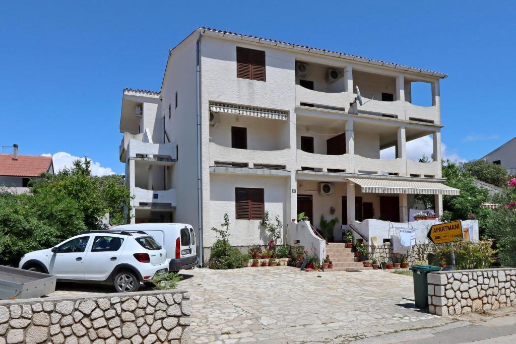 a white house with a car parked in front of it at Apartments by the sea Mandre, Pag - 3084 in Kolan