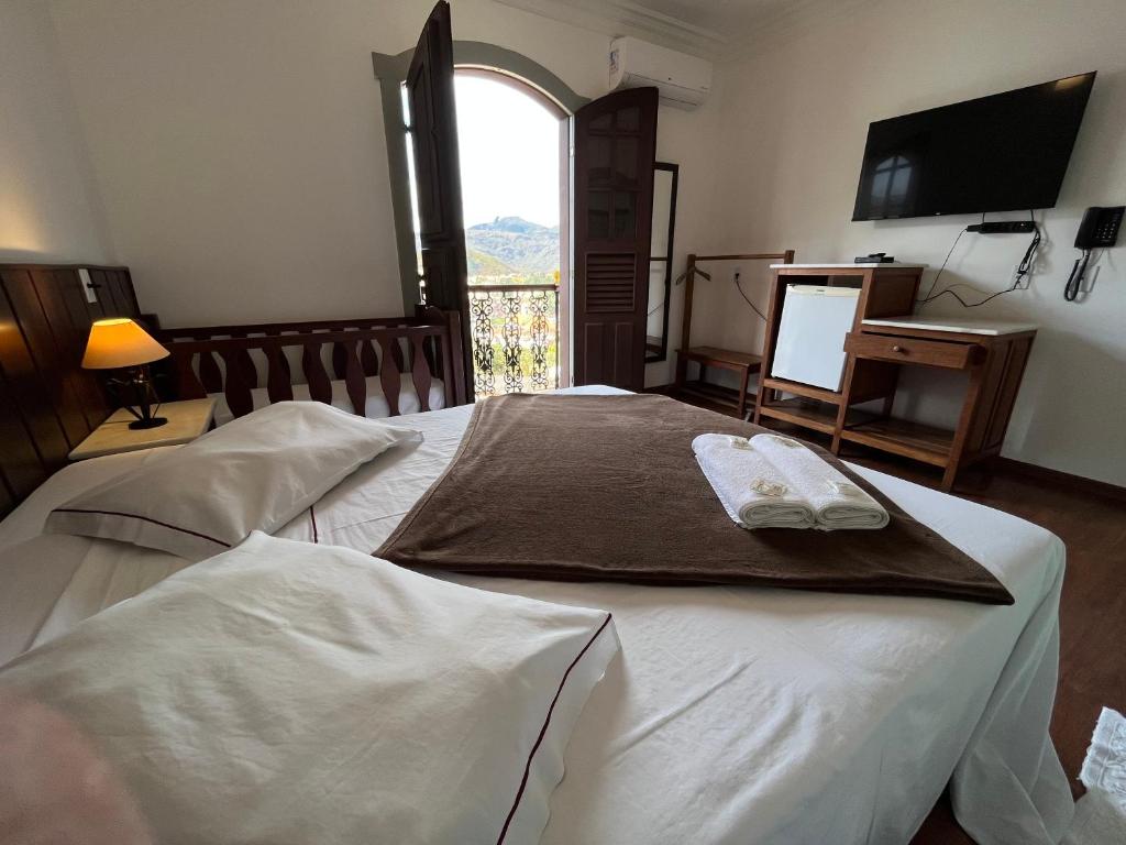 two beds in a room with a television and a window at Pousada Casa dos Contos in Ouro Preto