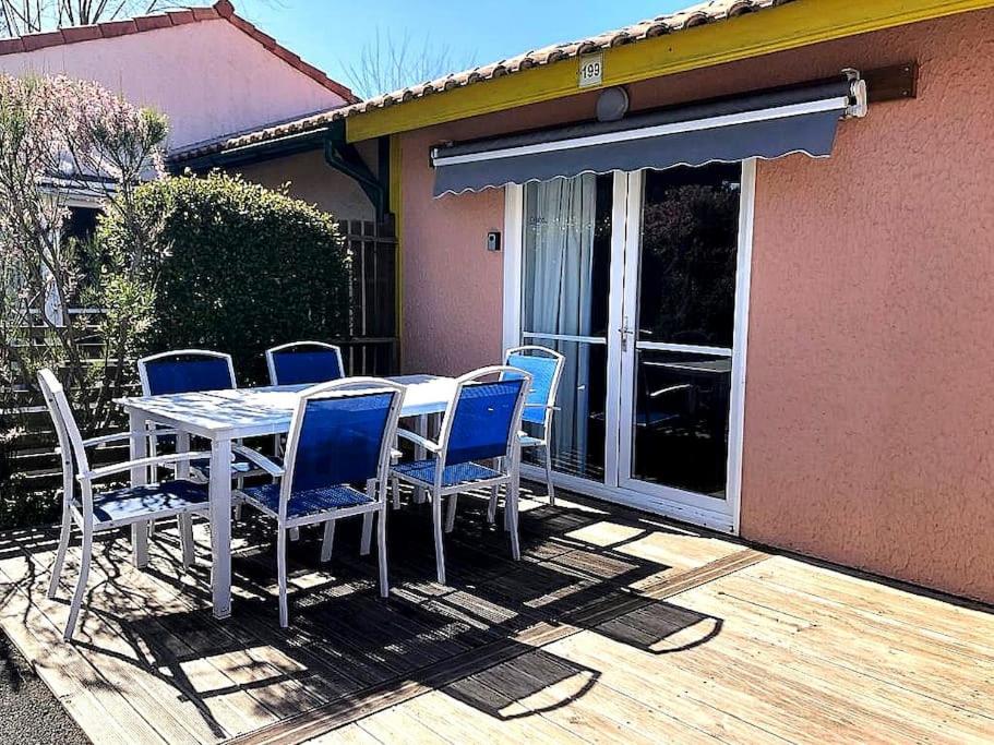 une table et des chaises sur une terrasse en bois avec une maison dans l'établissement Charmante petite maison, à Soustons