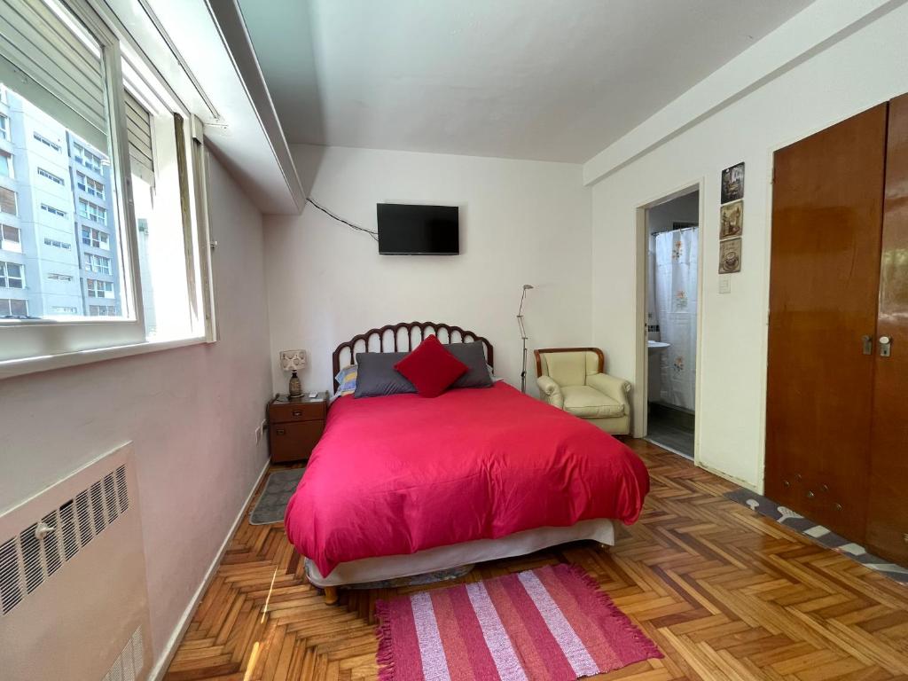 1 dormitorio con cama roja y ventana en Imperdible Monoambiente en Palermo Chico 10min Aeroparque 100m Mater Dei en Buenos Aires