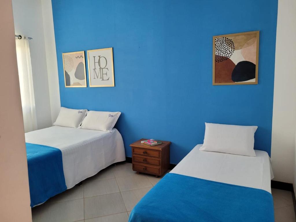 two beds in a room with a blue wall at Casas Rio de Contas in Rio de Contas