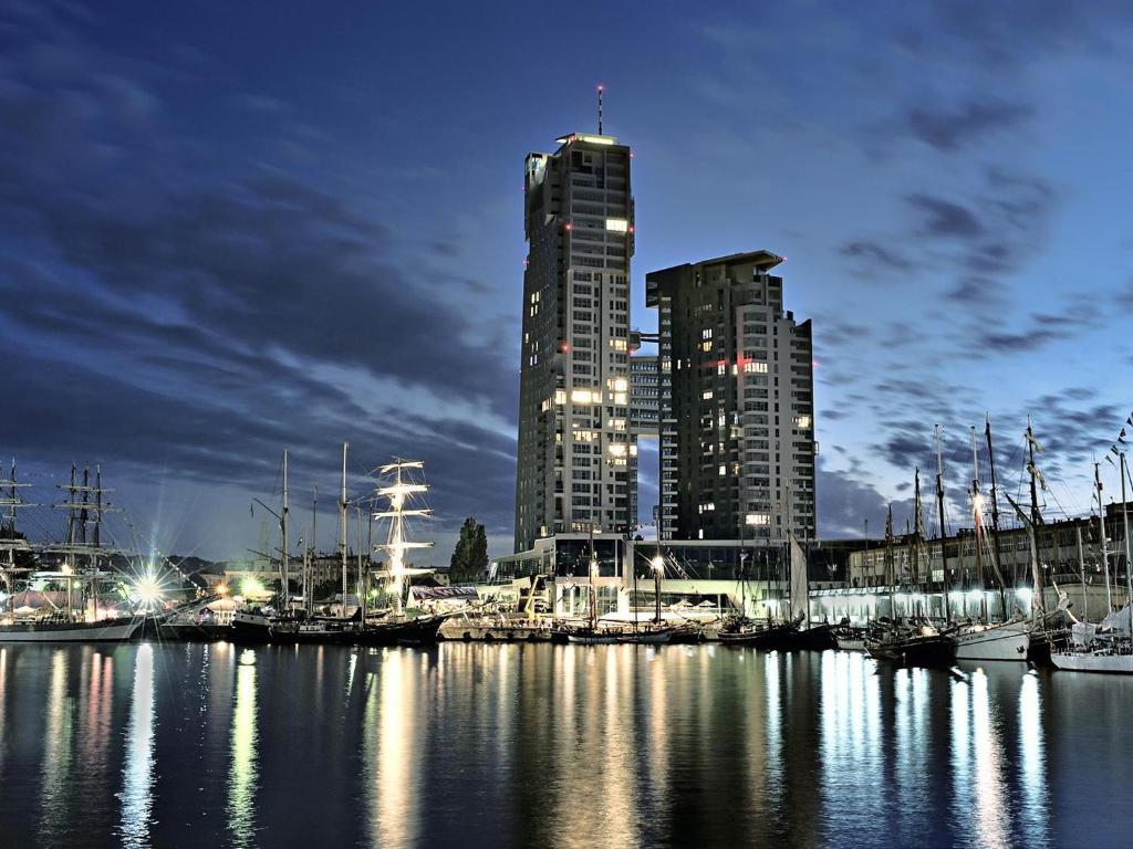 a harbor with boats in a city at night at Apartamenty Sea Towers in Gdynia