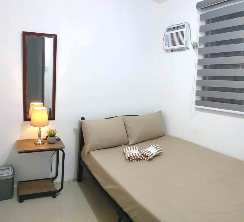 a small room with a bed and a table with a lamp at Rockmelon Guest House in Mabalacat