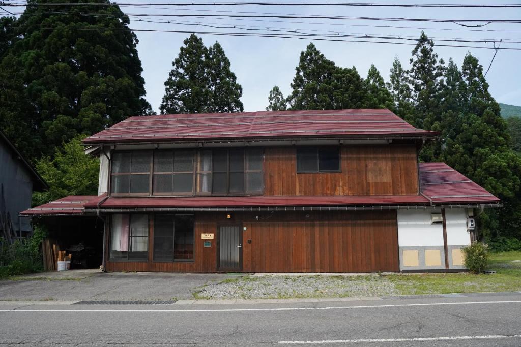 una casa di legno con il tetto rosso su una strada di WAY SHIRAKAWAGO - Private, Free Parking and Newly Opened 2022 WAY SHIRAKAWAGO a Shirakawa