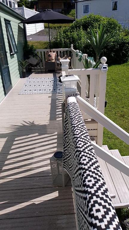 a wooden deck with a white fence and an umbrella at Brittany's in Gisburn