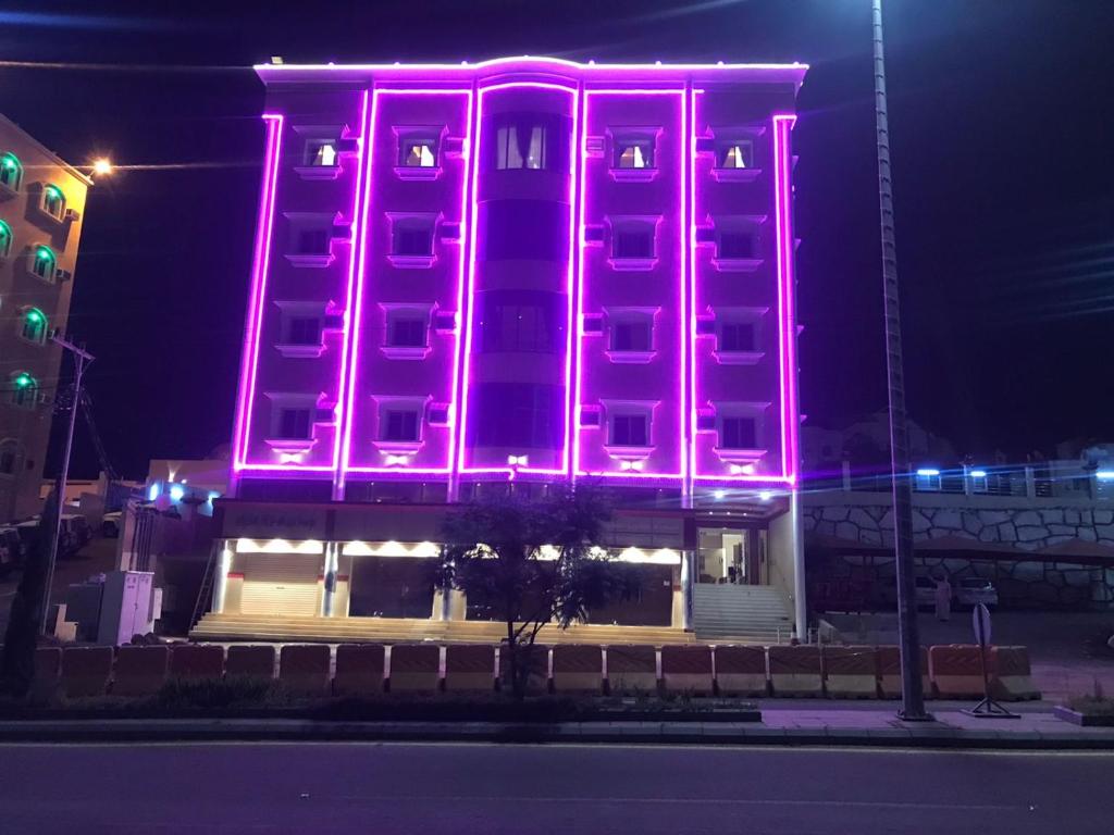 a building with pink lights on the side of it at فندق وشقق ليالي الاحلام للشقق المخدومه in Baljurashi