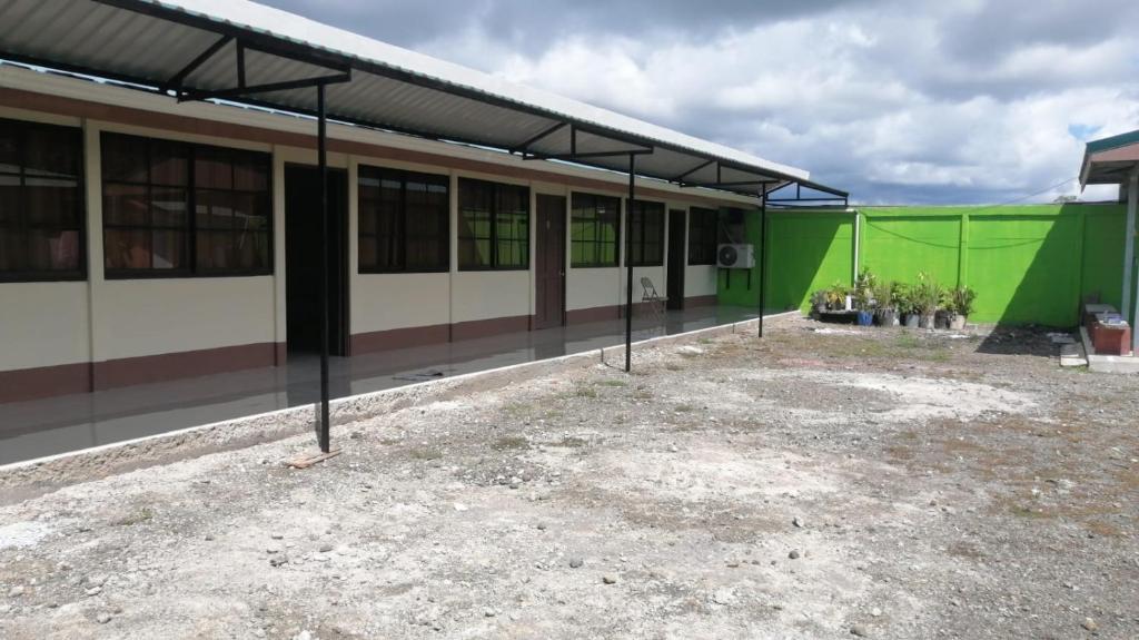 ein grün-weißes Gebäude mit einer grünen Wand in der Unterkunft Cabinas Lawson in Puerto Jiménez
