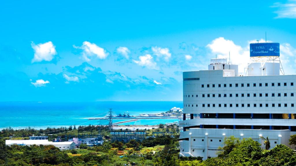 a large white building with the ocean in the background at Rycom Crystal Hotel in Okinawa City