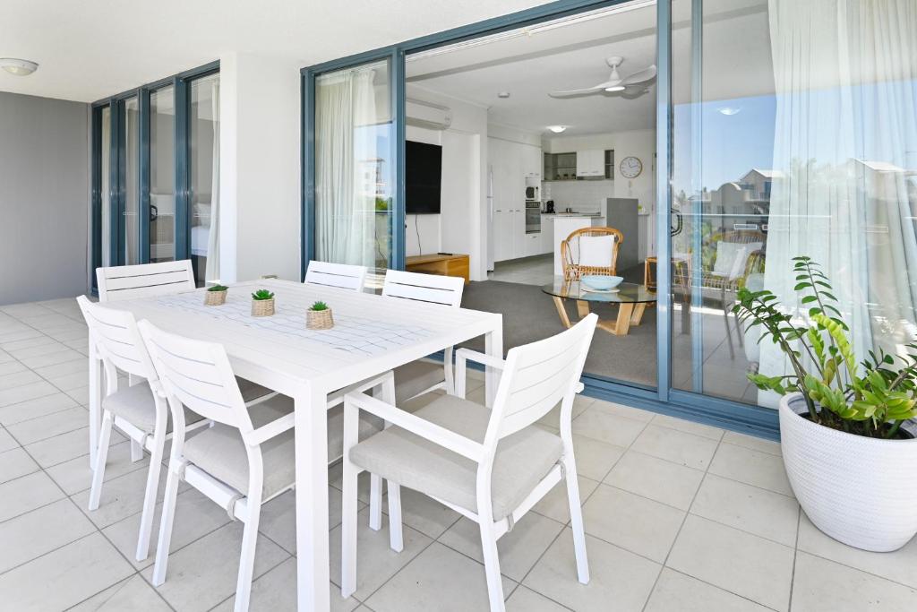 a white dining room with a white table and chairs at Alexandra Headland Resort Heaven, Pool / Beach ZD8 in Alexandra Headland