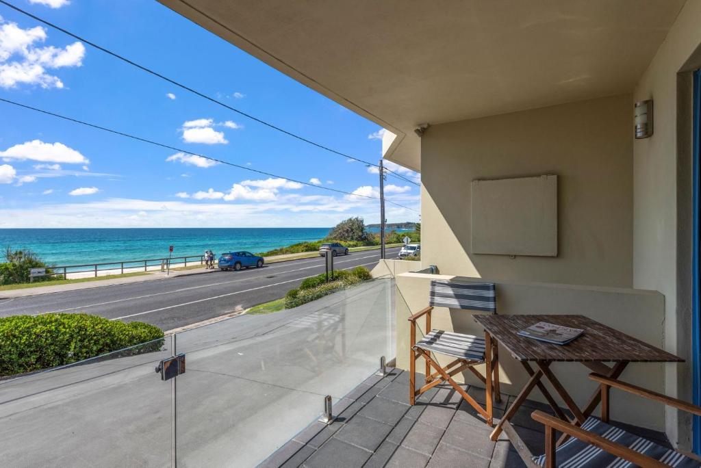 a balcony with a table and a view of the ocean at Aqua Shores Studio in Mollymook
