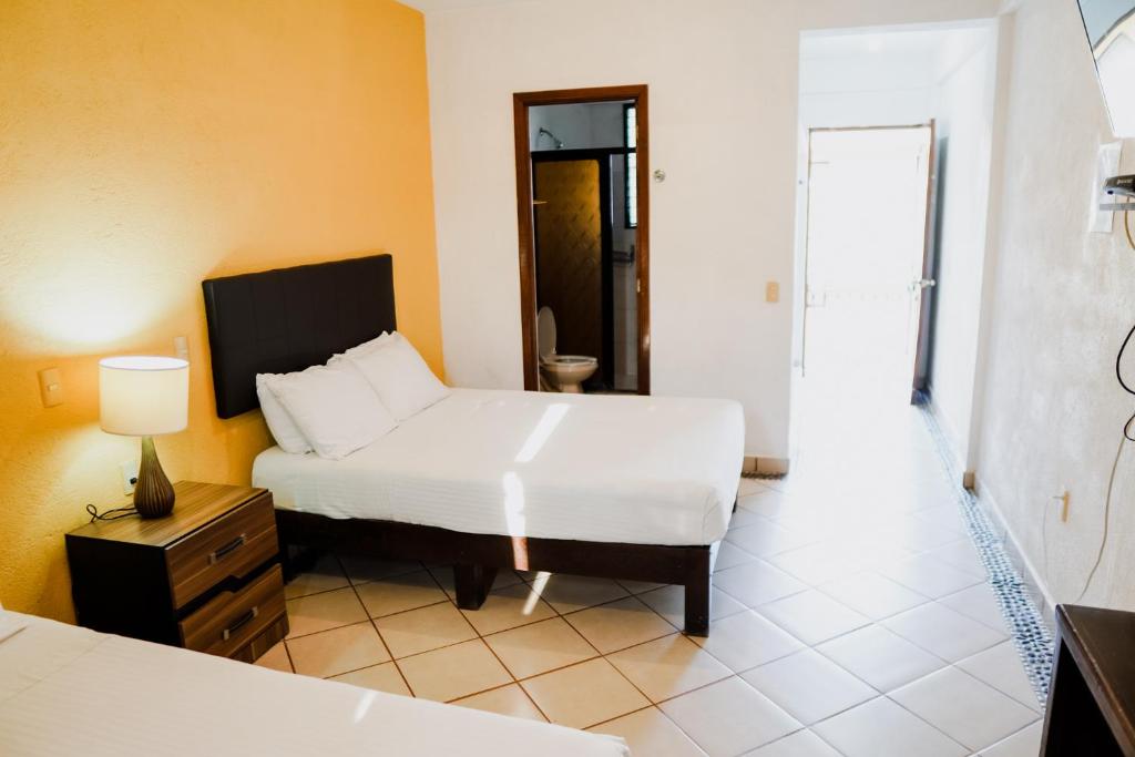 a bedroom with a bed and a table and a lamp at HOTEL ROBLE ZIHUATANEJO in Zihuatanejo