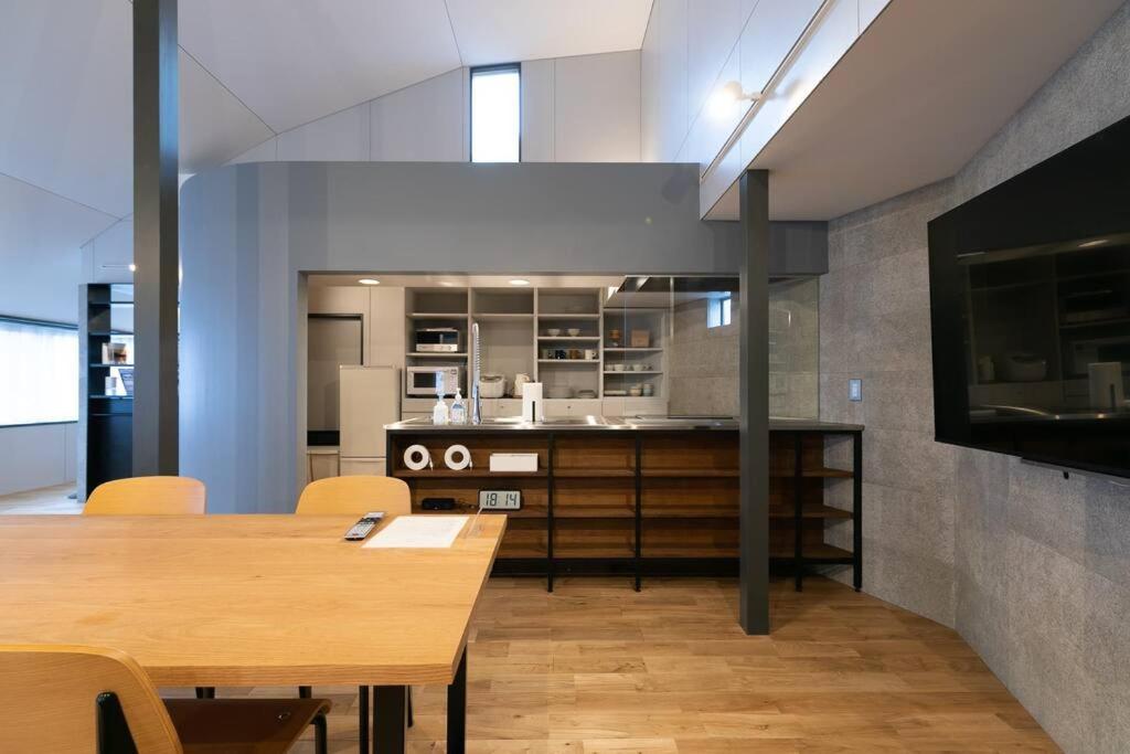 a kitchen and dining room with a table and a tv at Social Guest House neltoko in Nanao