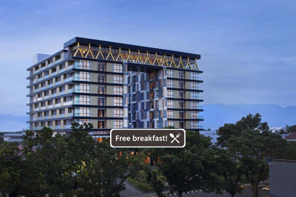 a free breakfast sign in front of a tall building at Hotel Santika Premiere Padang in Padang