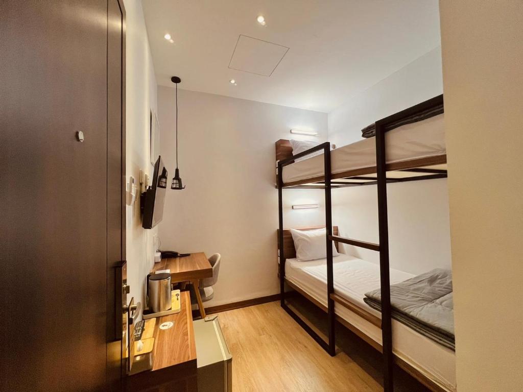 バタム・センターにあるoxy suites G-03 at Shop House Meisterstadt Pollux Habibieの二段ベッド2台、デスクが備わる小さな客室です。