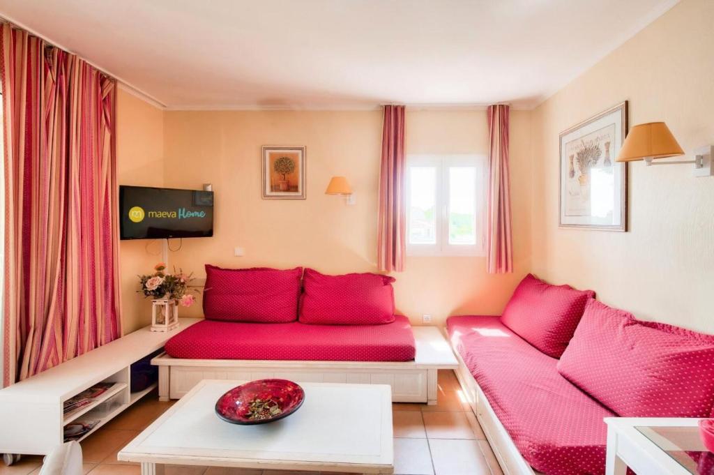 ein Wohnzimmer mit einem roten Sofa und einem TV in der Unterkunft Village Pont Royal en Provence - maeva Home - Appartement 2 pièces 6 person 034 in Mallemort