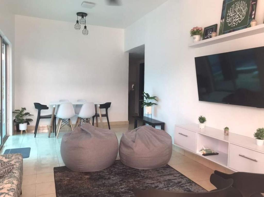 uma sala de estar com 2 pufes e uma televisão em Garlic Cherating Pool Homestay em Kampong Baharu Cherating