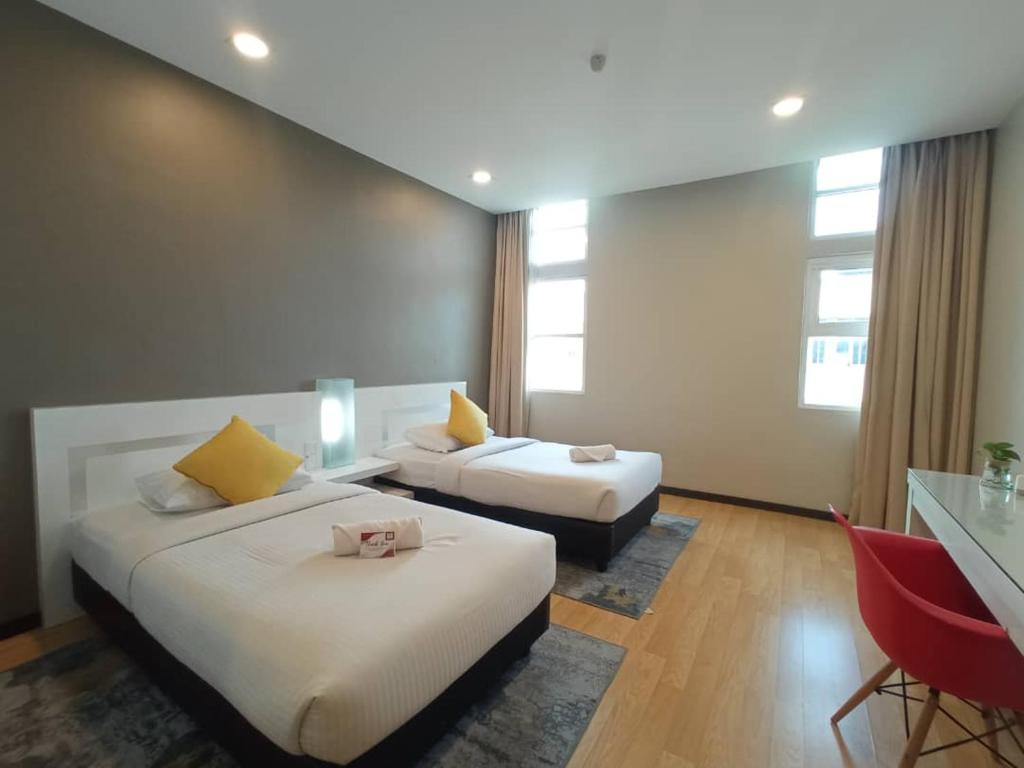 a hotel room with two beds and a desk at Lovita Hotel Kuantan in Kuantan