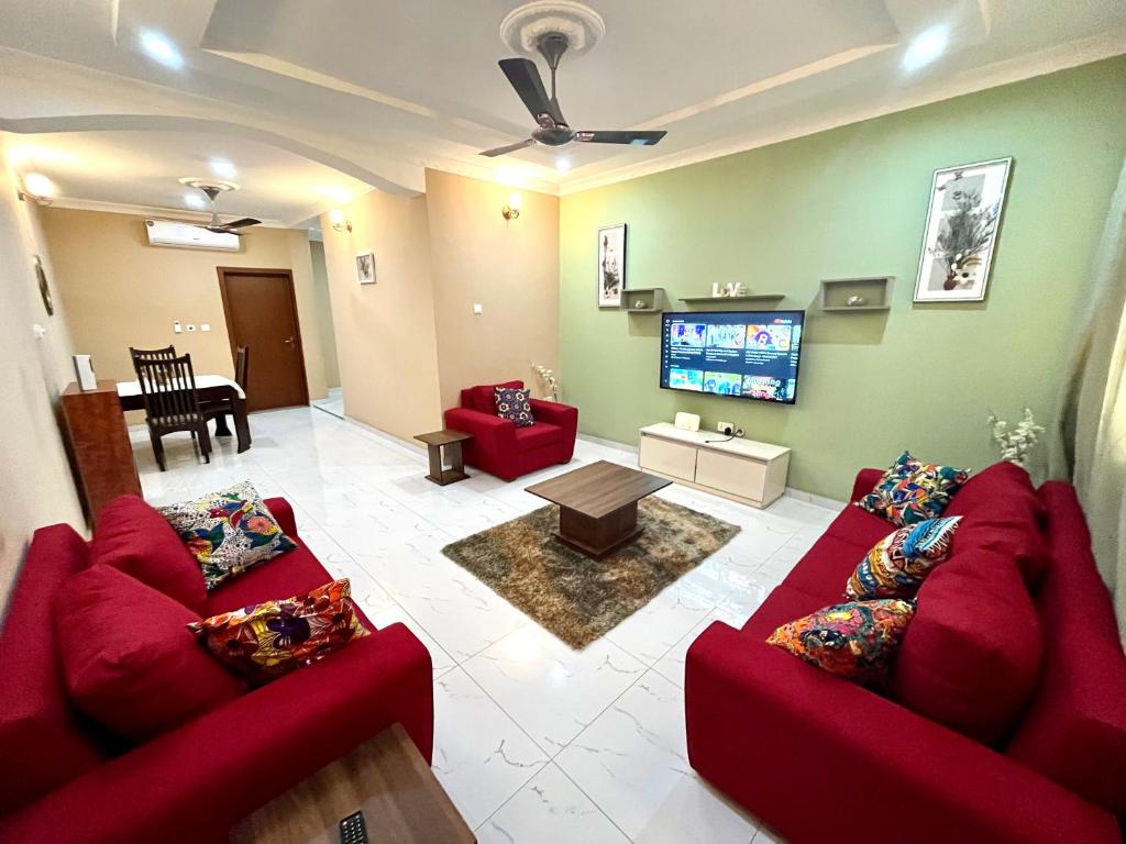 een woonkamer met twee rode banken en een televisie bij Hidden Gem In Oyibi New 2 Luxury Bedroom Apartment in Aburi