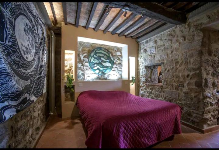 a bedroom with a purple bed in a stone wall at Elettra Flower Roccia in Montecatini Val di Cecina