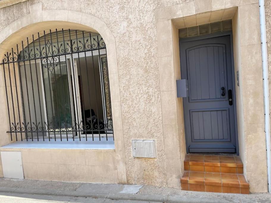 a building with a blue door and a gate at Charmant logement proche de la mer in Florensac