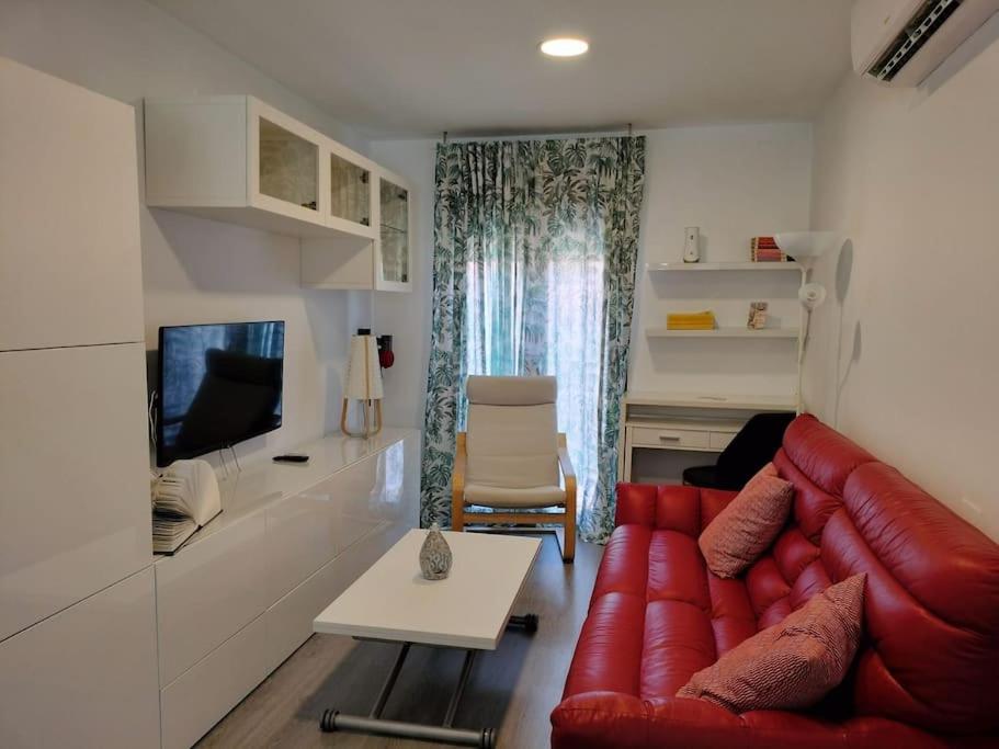 sala de estar con sofá rojo y TV en Apartamento El Hidalgo, en Alcalá de Henares