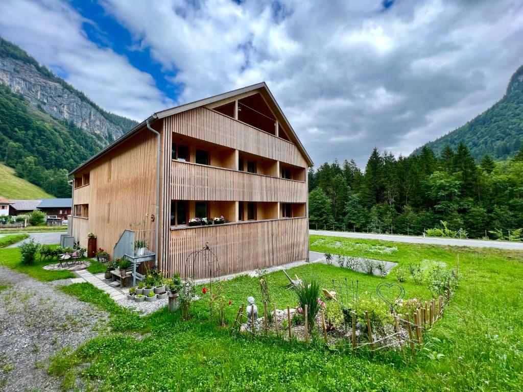 a wooden building in a field with mountains in the background at Apartment Eiler - Mellau in Mellau