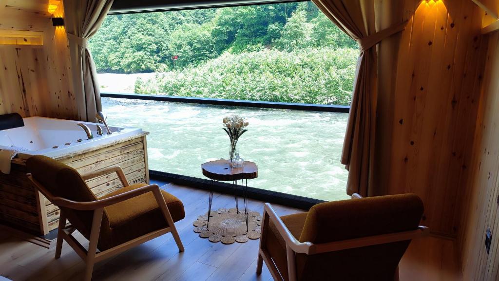 a bathroom with a tub and chairs and a large window at Serinle Bungalow in Rize