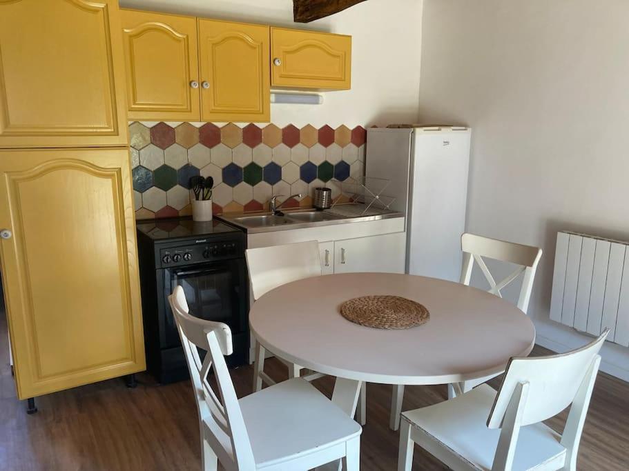 eine Küche mit einem weißen Tisch und Stühlen sowie einem weißen Kühlschrank in der Unterkunft Maison, Le Champ du Rossignol in Beuvron-en-Auge