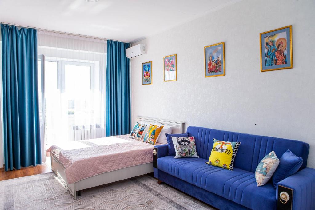 um sofá azul e uma cama num quarto em Студия в центре города, в «Золотом квадрате» em Almaty