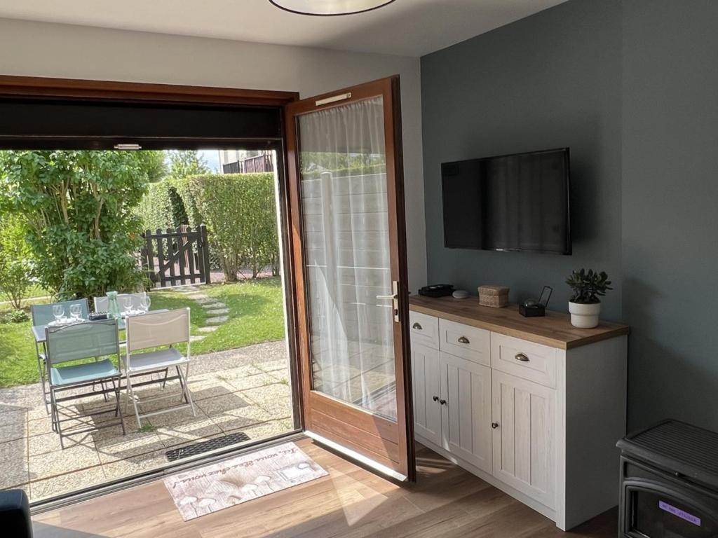 un salon avec une porte coulissante en verre et une télévision dans l'établissement **Cottage 6 pers à Cabourg - Proche plage et thalasso, jardin, parking, Wi-Fi gratuit** - FR-1-487-358, à Cabourg