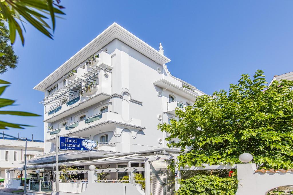 a white building with a blue sign in front of it at Hotel Diamond in Riccione