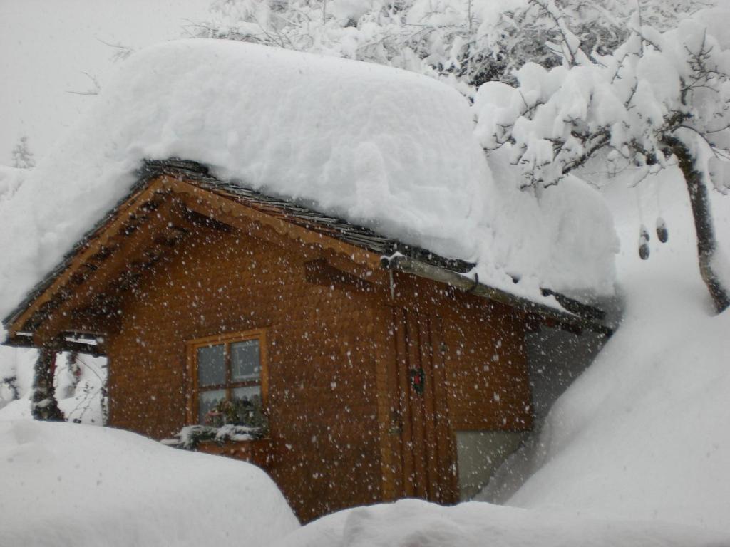 a snow covered cabin with a pile of snow on the roof at Haus Baleisa in Gaschurn