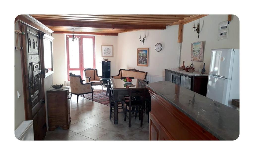 eine Küche und ein Wohnzimmer mit einem Tisch und einem Kühlschrank in der Unterkunft Paydos Tatil Evi in Ayvalık