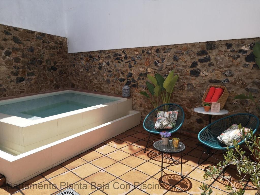 Apartamentos Durán Pizarro 1930 في ماردة: حوض استحمام في غرفة مع كرسيين