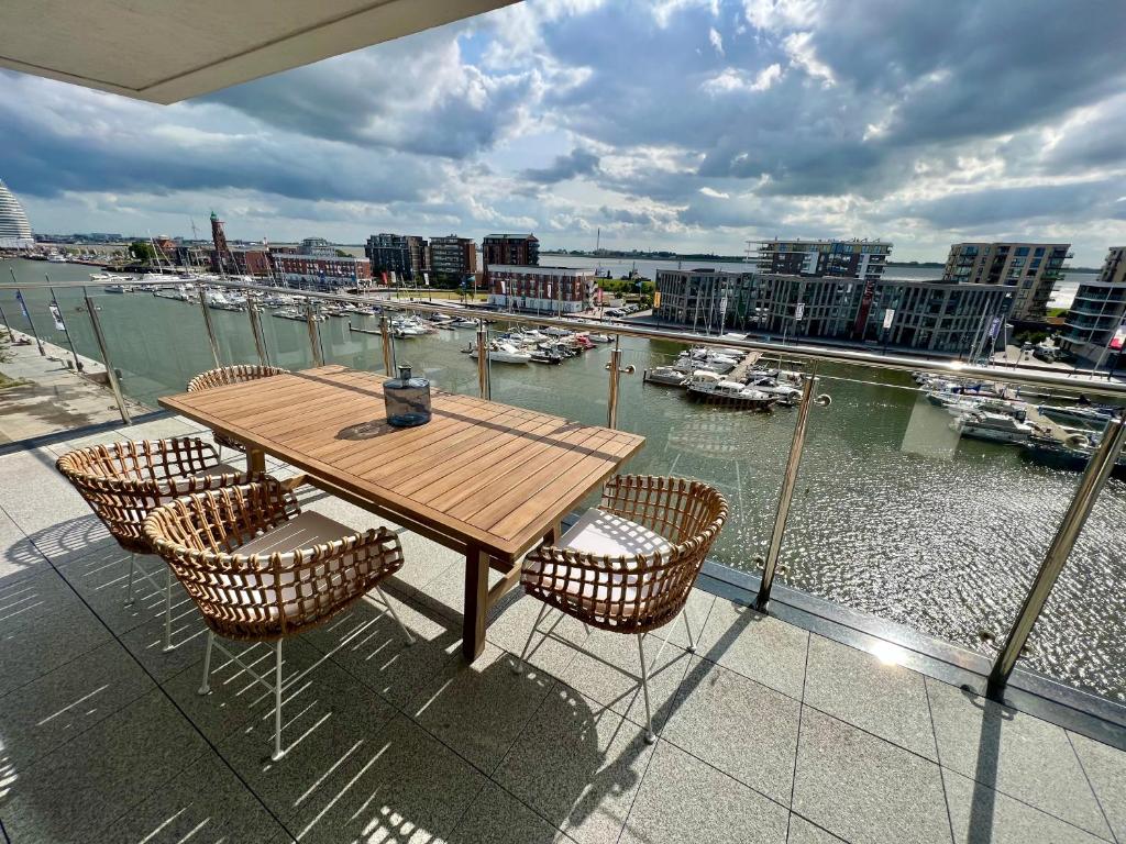 a wooden table and chairs on a balcony with a harbor at COAST HOUSE Seaside Loft in Bremerhaven