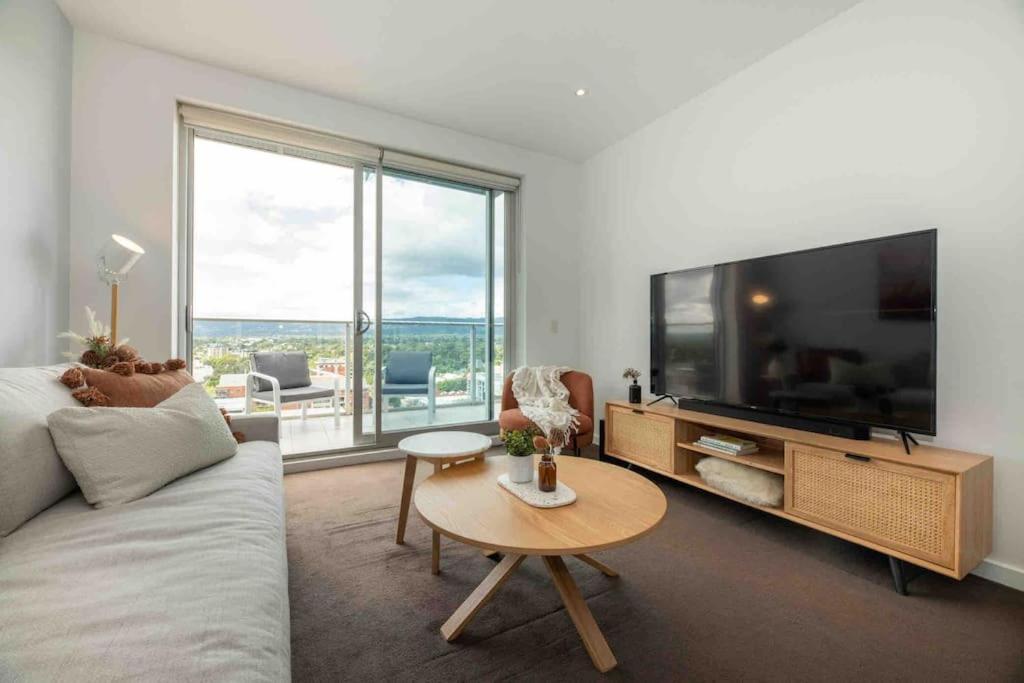 a living room with a couch and a tv and a table at City apartment, pool & carpark in Adelaide