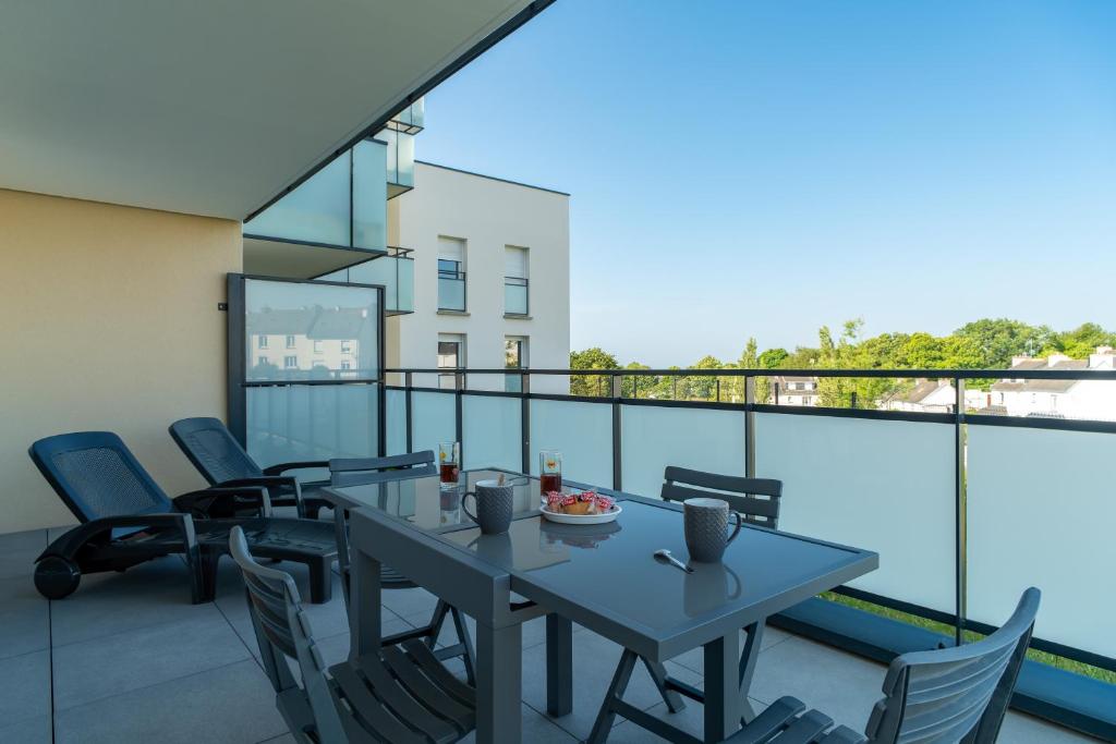 un patio avec une table et des chaises sur un balcon dans l'établissement Sioul - Appt à moins d1km de la plage, à Concarneau