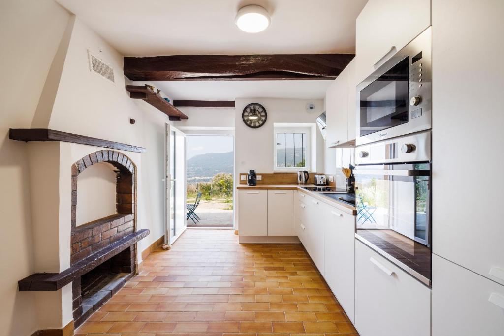 eine Küche mit weißen Schränken und einem gemauerten Kamin in der Unterkunft Le Masage - Appt pour 6 vue montagne in Castagniers