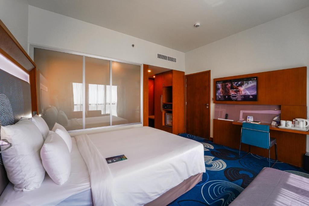 a hotel room with a large bed and a television at Novotel Fujairah in Fujairah