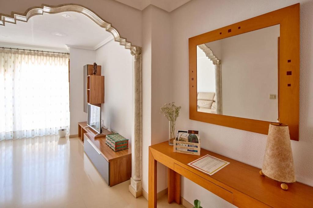een woonkamer met een spiegel en een houten tafel bij ECO-MANOLITA in Elche