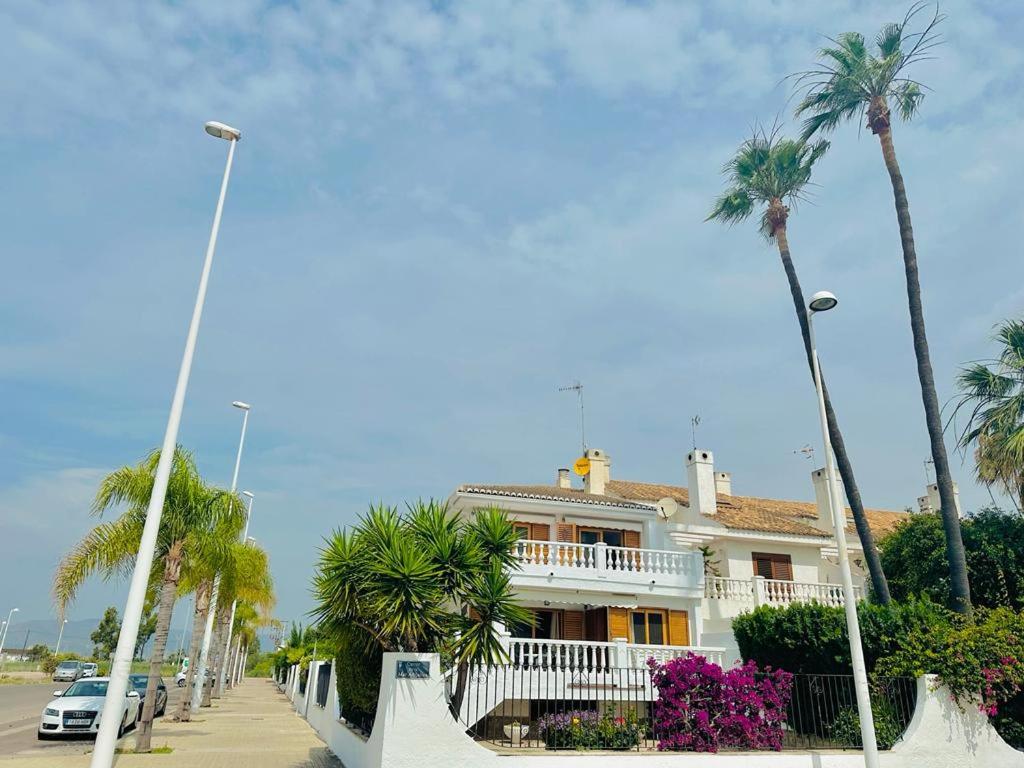 a white house with palm trees on a street at Valencia Sol y Playa in Sagunto