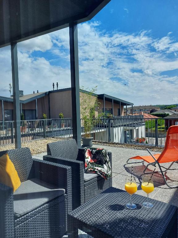 patio z krzesłami i 2 kieliszkami soku pomarańczowego w obiekcie Paskom Apartmanház w mieście Nyergesújfalu