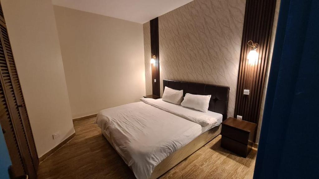 a bedroom with a bed with white sheets and pillows at شاليه البرادايس درة العروس in Durat  Alarous