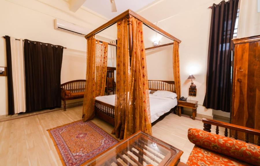 a bedroom with a canopy bed with a mirror at Sisodia Hotel & Resorts in Jodhpur