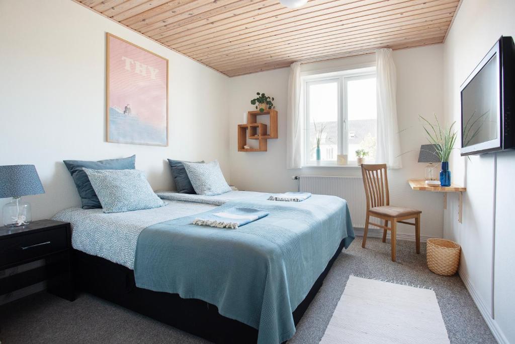 a bedroom with a bed and a chair and a window at Stone Mountain BnB in Stenbjerg