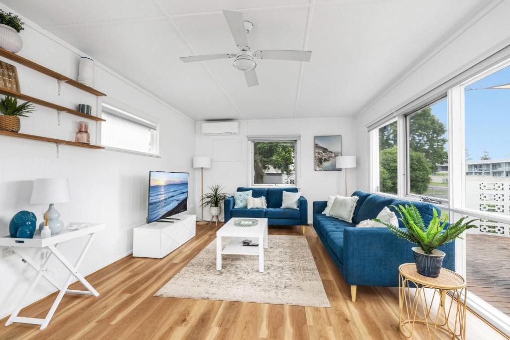 a living room with a blue couch and a table at Coastal Cottage Batemans Bay in Batemans Bay